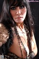 A woman with long black hair wearing a fur coat.