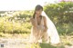 A woman in a white dress crouching down in a field.