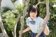 A woman in a school uniform leaning against a tree.