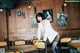 A woman in a white blazer and black stockings leaning on a table.