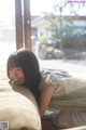 A woman laying on top of a couch next to a window.