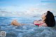 A woman in a bikini laying in the ocean.